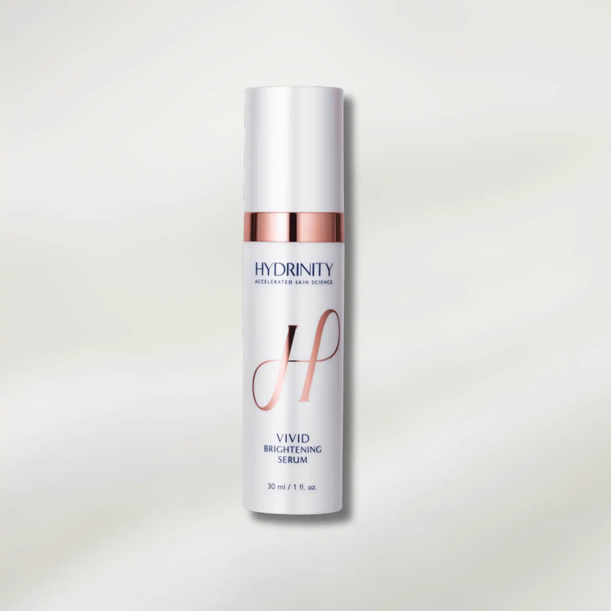 A 30 ml bottle of Hydrinity Vivid Brightening Serum, featuring a white cylindrical bottle with a metallic rose gold collar and elegant gold monogram logo, set against a clean off-white background with soft shadows.