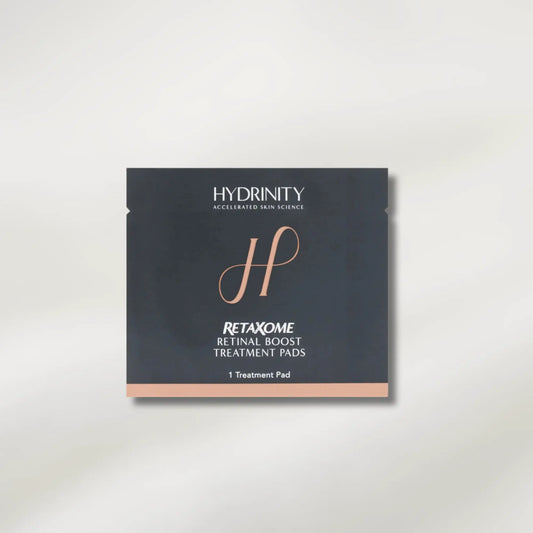 A single square skincare treatment pad packet from Hydrinity, featuring a dark charcoal gray background with rose gold accents and white text, centered on a light beige background.